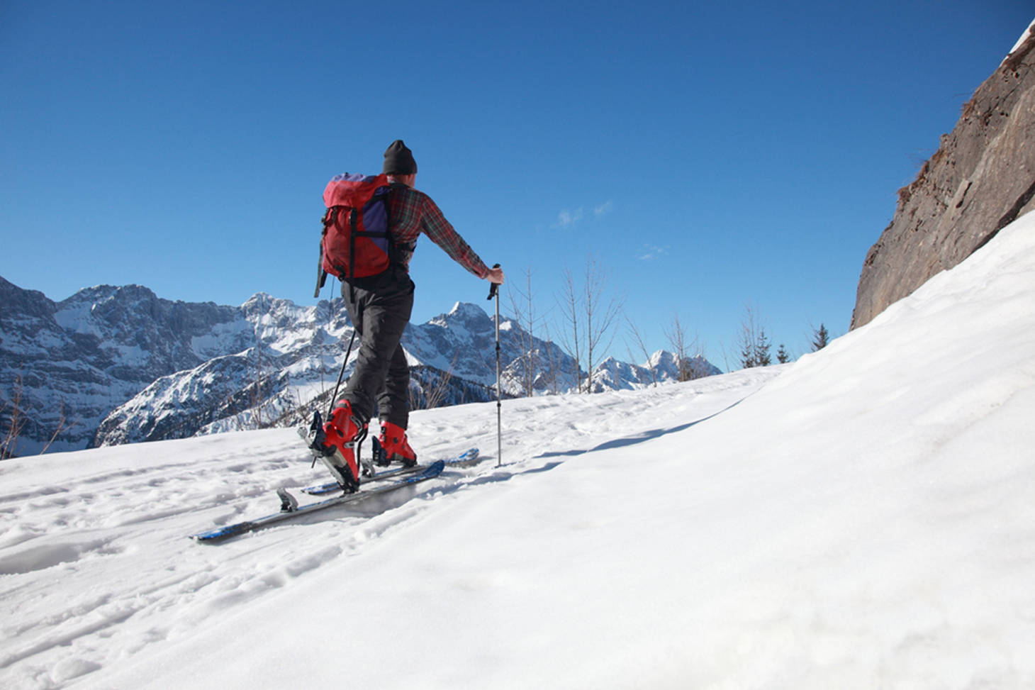 Un skieur de randonnée gravit une pente enneigée